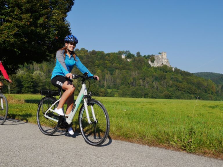 Radfahrer auf E-Bikes mit Burgruine Neideck im Hintergrund